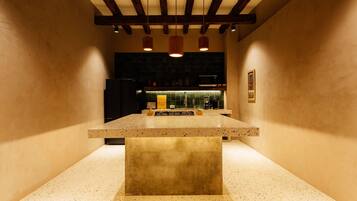 A kitchen with a central island, dark cabinetry, and pendant lighting.