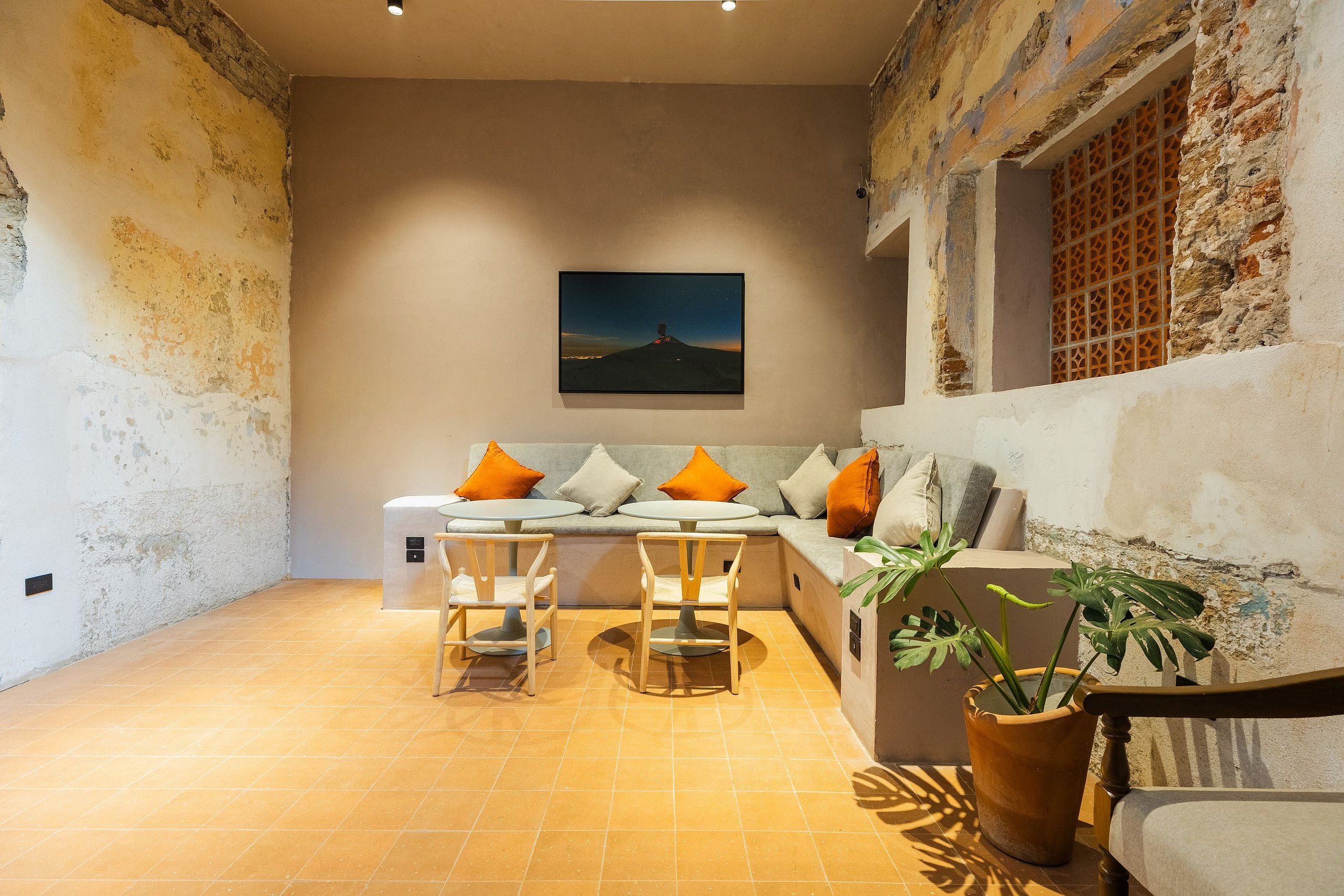 A cozy living area with a sofa, two chairs, a table, and a potted plant.