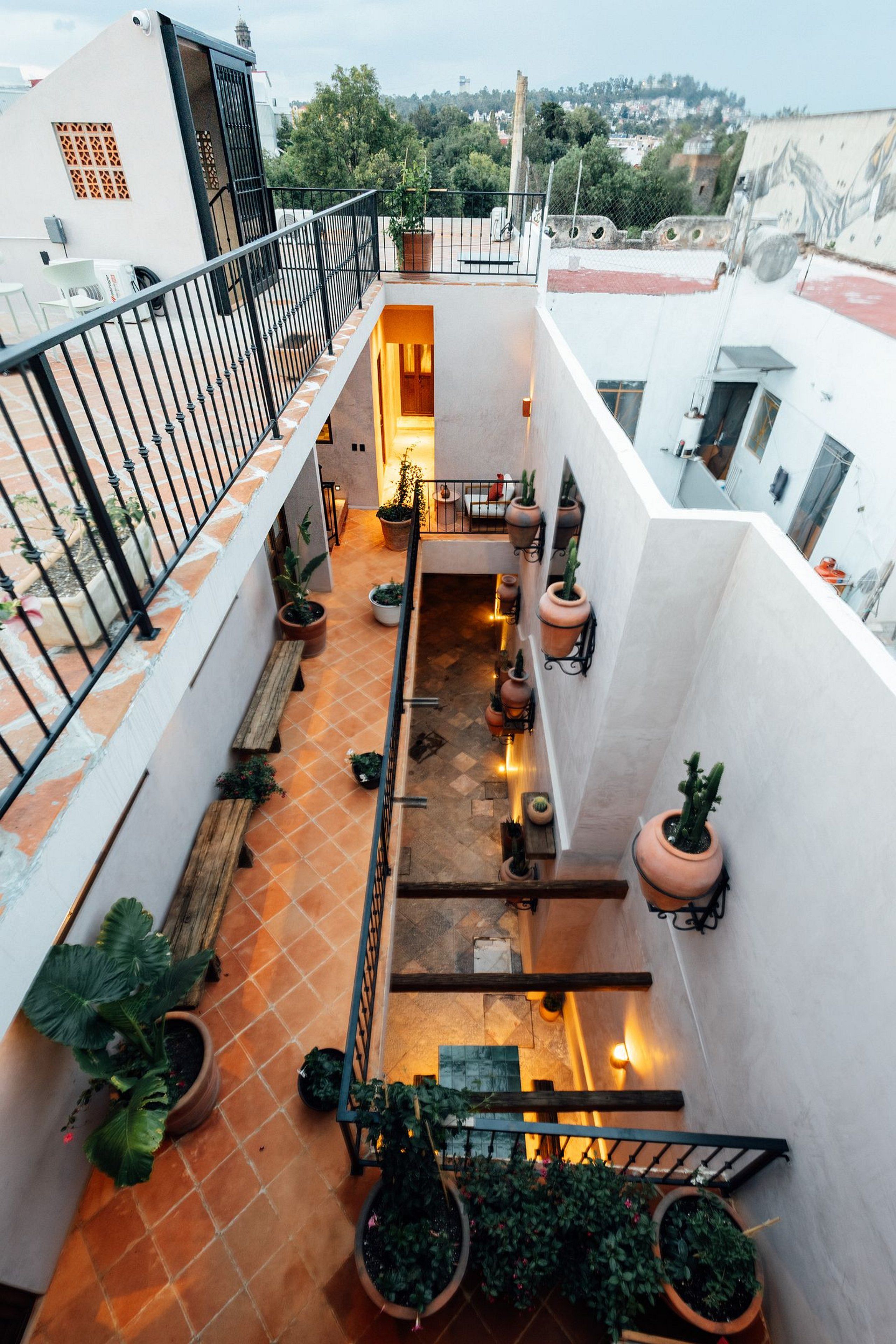 A multi-level outdoor terrace with potted plants, a wooden bench, and a view of the surrounding area.
