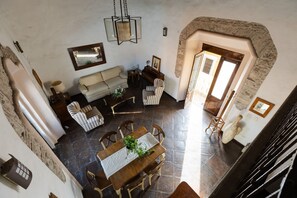 A spacious living area with a high ceiling, a stone archway, a dining table with chairs, a sofa, and a hanging light fixture. - Casa La Virgen | Washing machine + Parking (Heroica Puebla de Zaragoza)