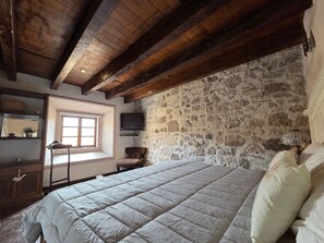 A bedroom with a stone wall, a bed with white bedding, a wooden ceiling, and a window. - Casa La Virgen | Washing machine + Parking (Heroica Puebla de Zaragoza)