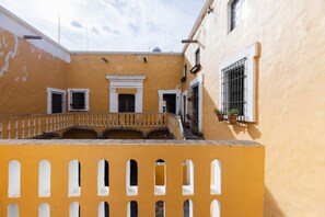 A courtyard with a yellow building, a balcony, and a window with a plant. - Casa La Virgen | Washing machine + Parking (Heroica Puebla de Zaragoza)