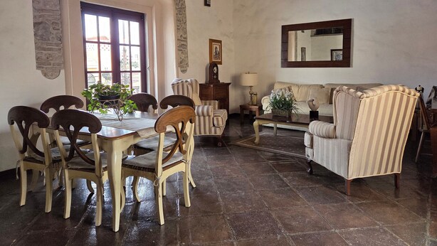 Un coin repas agrémenté d’une arche en pierre, d’une table à manger avec des chaises, d’un canapé et d’une lampe.
