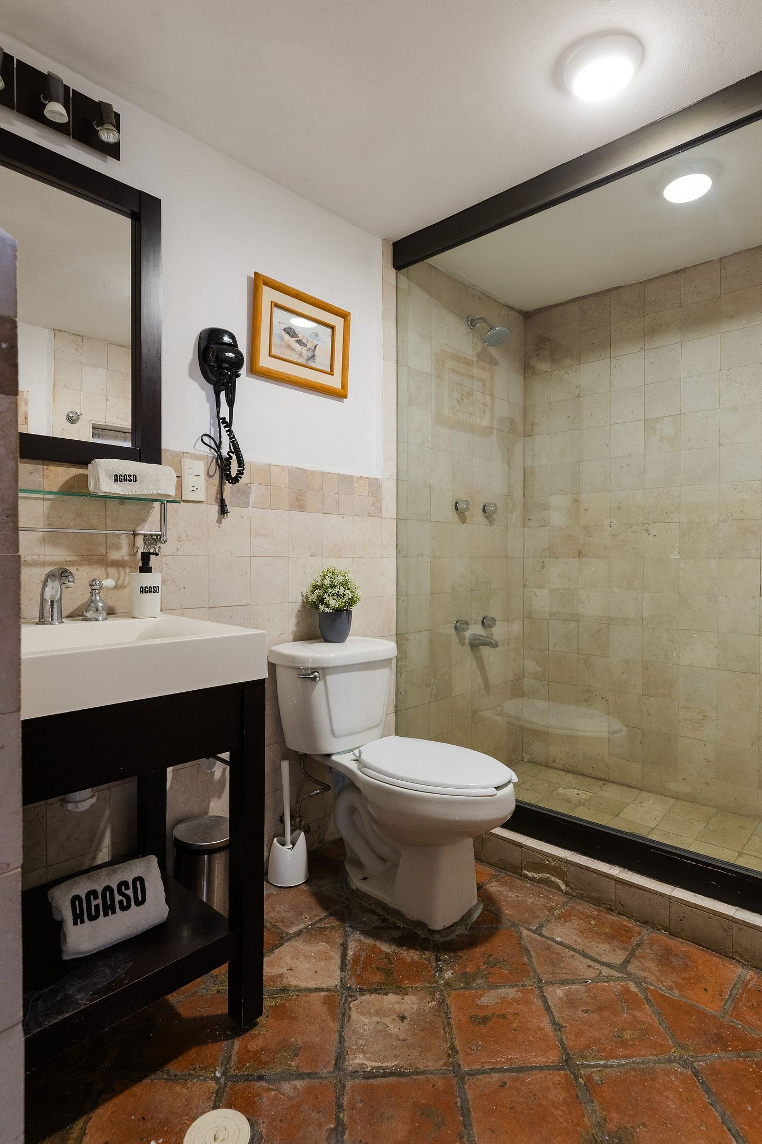 A bathroom with a toilet, sink, and shower.
