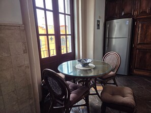 A kitchen with a round glass table, wicker chairs, a refrigerator, and a view through a window with a door. - Casa La Virgen | Washing machine + Parking (Heroica Puebla de Zaragoza)