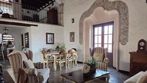 Un vaste salon doté d’un haut plafond, un coin repas avec une table et des chaises, et un escalier menant à un niveau supérieur.