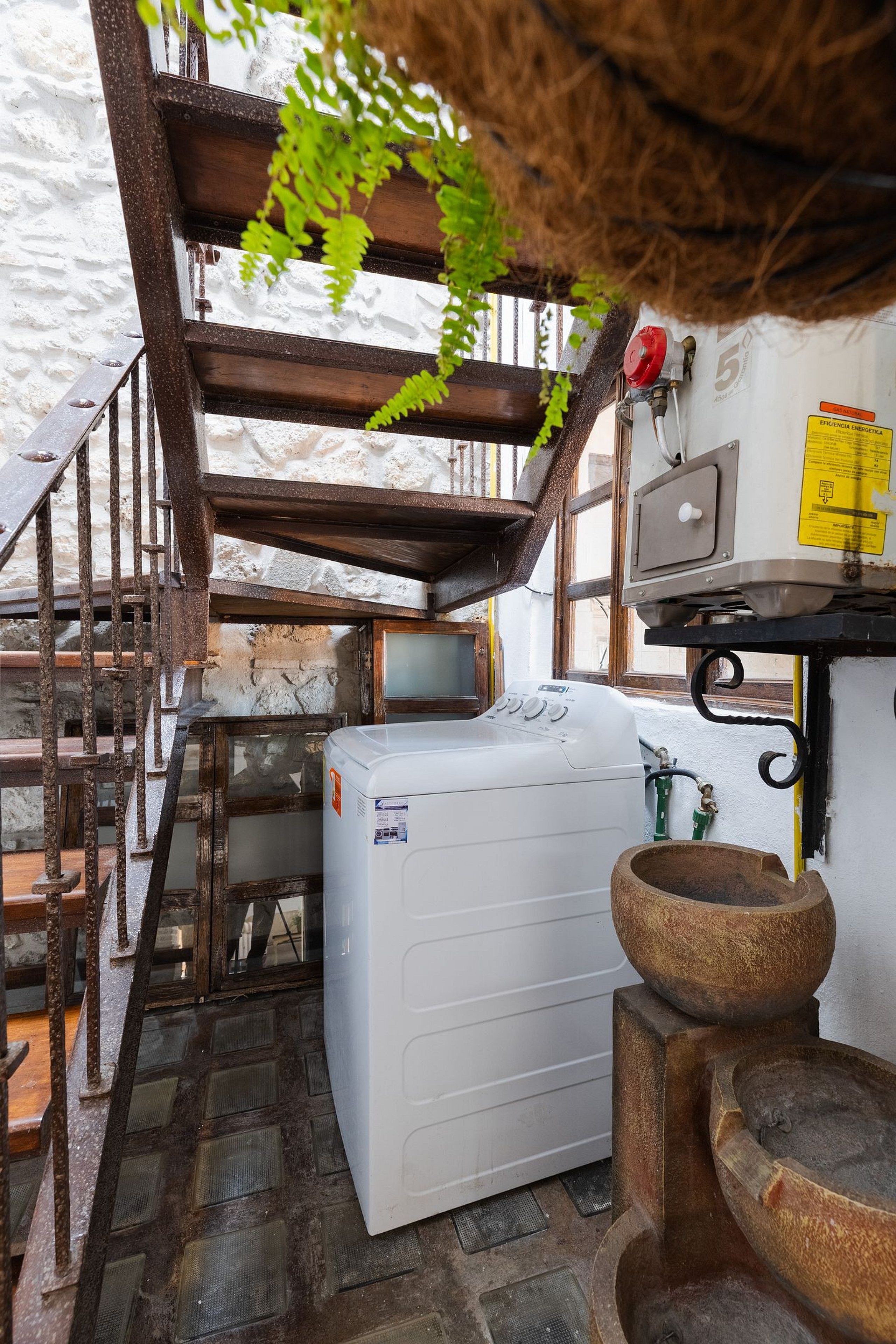 Une cuisine rustique équipée d’un lave-linge, d’un évier et d’un tabouret en bois.
