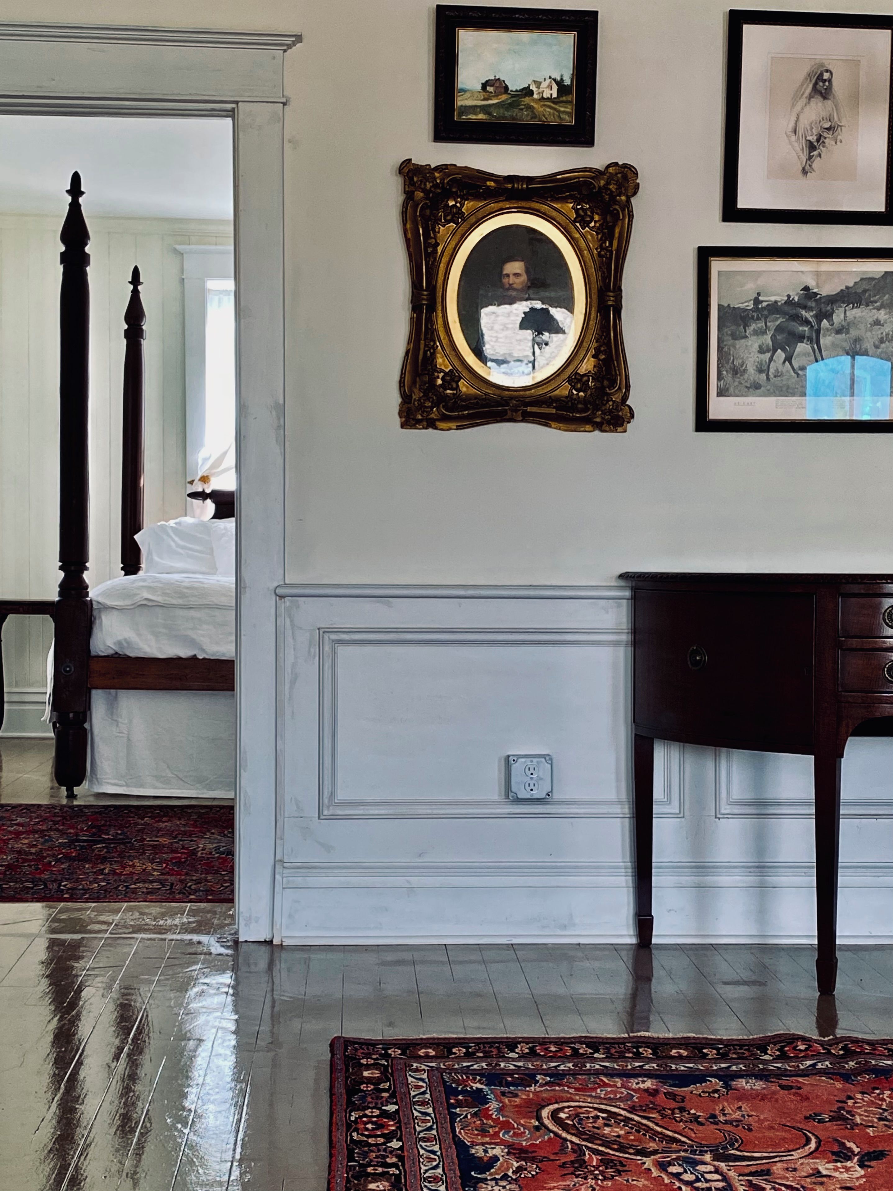 A room with a bed, a mirror, and a dresser. There is a rug on the floor.