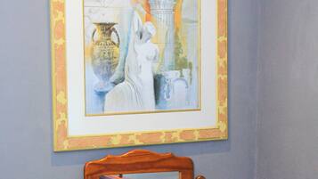A framed artwork above a wooden dresser with a mirror reflecting part of the room.