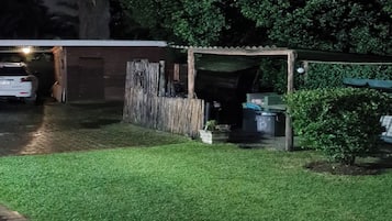 Vista nocturna de una zona residencial con césped cuidado, una valla de madera y un garaje.
