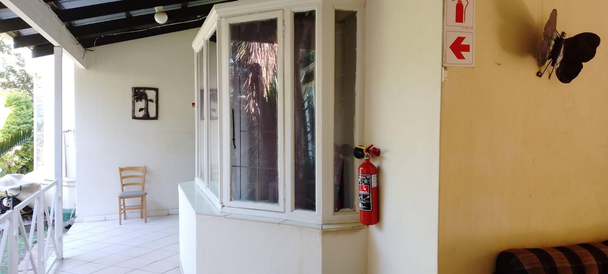 Ein Zimmer mit Fenster, Feuerlöscher, Stuhl und einem an der Wand befestigten Schild.