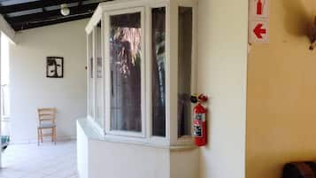 Une pièce avec une fenêtre, un extincteur, une chaise et un panneau fixé au mur.