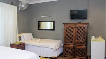 Une chambre à coucher comprenant un lit, une armoire, un téléviseur et un petit réfrigérateur.