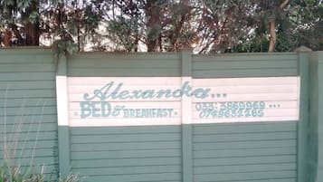 Una puerta verde con un cartel que indica 'Alexandra Bed & Breakfast', incluyendo un número de teléfono.