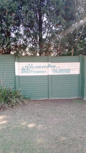 A green gate with a sign for 'Alexandra Bed & Breakfast' including a phone number.