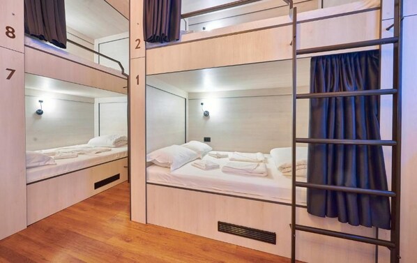A dormitory room with bunk beds, each with a number on the wall, and a ladder attached to the right side.