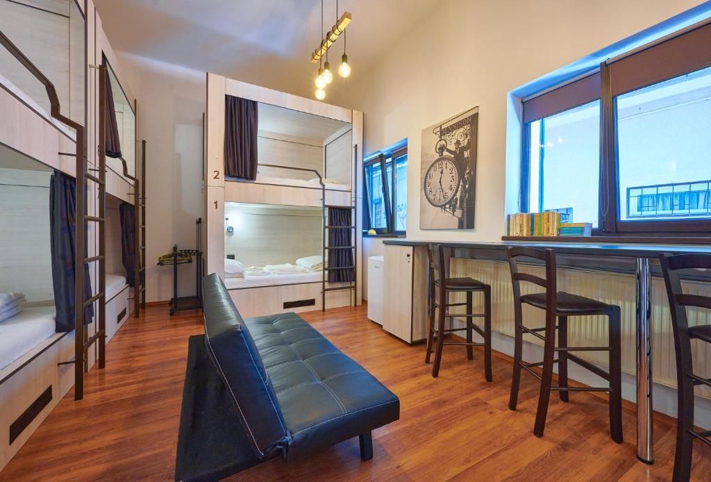 Habitación compacta con literas, una banca, kitchenette y una ventana que proporciona luz natural.