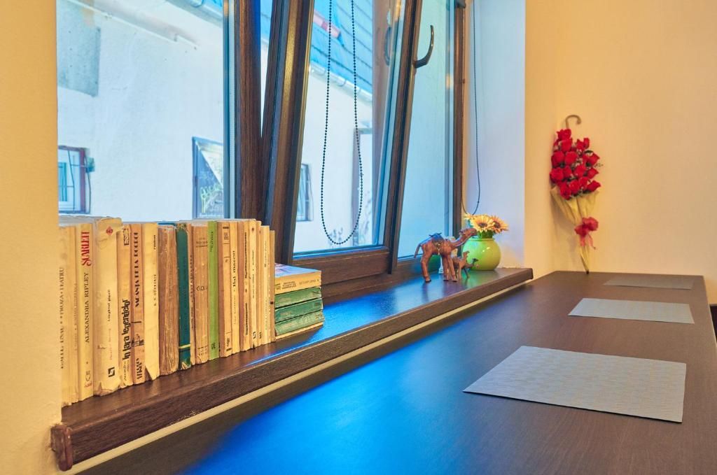 A window sill with books, a small figurine, and a vase with flowers.