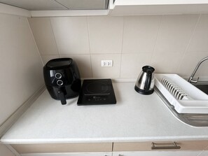 A kitchen with a coffee maker, a kettle, and a power strip on the countertop. - Stylish Bangkok Escape Pool Gym & City Views (Bangkok)
