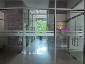 A hallway with glass doors, a tiled floor, and a view of greenery outside. - Stylish Bangkok Escape Pool Gym & City Views (Bangkok)