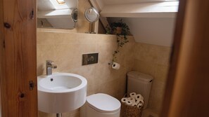 A bathroom with a white sink, a toilet, a mirror, and a shower area. - The Old Print House (Ilkeston)