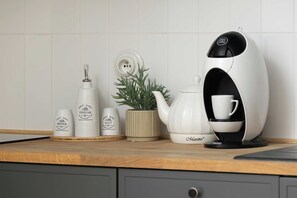 A kitchen counter with a coffee machine, a kettle, and condiment containers. - Practical Studio with a Balcony | Parking (Warszawa)