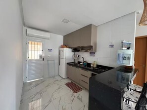 Eine moderne Küche mit Marmorboden, einem Kühlschrank, einer Spüle und einem Wasserspender.