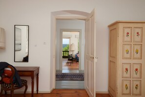 Ein Flur mit Holzboden, einer Tür, die auf einen Balkon führt, und einem Schrank mit floralen Verzierungen.