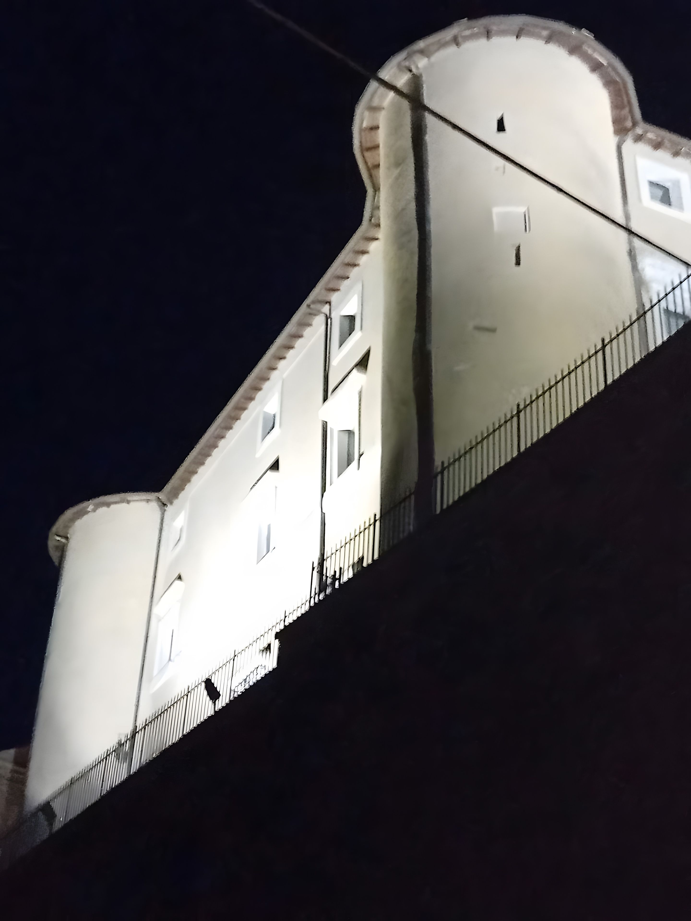 Un edificio con fachada curva y barandilla de balcón.