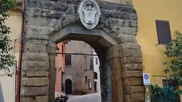 Ein steinernes Tor mit Wappen, das zu einer Kopfsteinpflasterstraße führt.