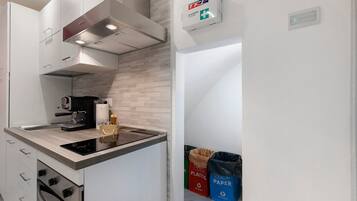 Una cocina moderna con estufa integrada, máquina de café y un botiquín de primeros auxilios en la pared.
