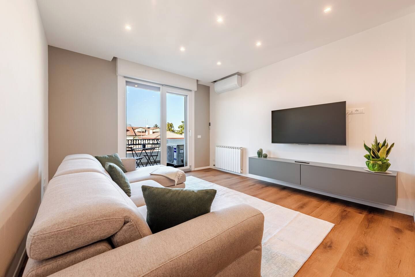 Un soggiorno moderno con un divano, una TV a schermo piatto e un termosifone.