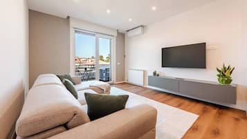 Un soggiorno moderno con un divano, una TV a schermo piatto e un termosifone.