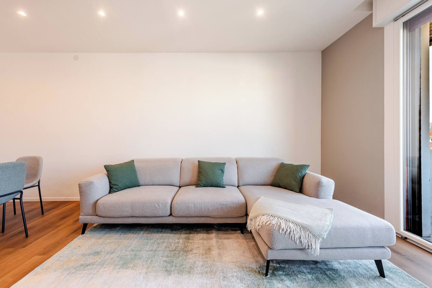 Ein modernes Wohnzimmer mit einer Couch, einem Sessel und einem großen Fenster.