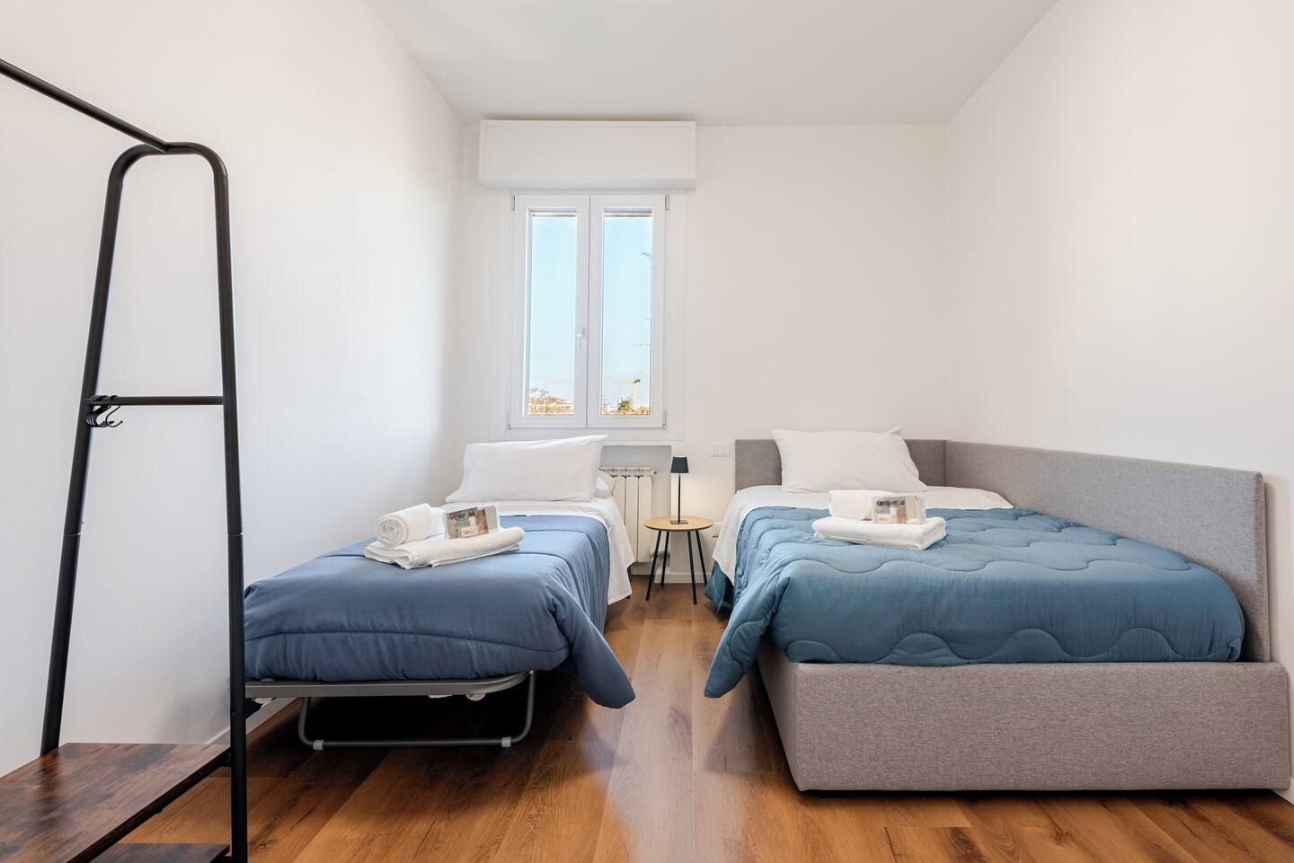 A compact room with two beds, a small table, and a window.