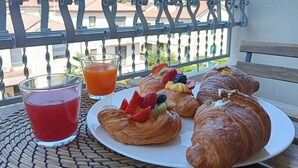 A balcony with a table set for breakfast, including croissants, fruit, and a glass of orange juice. - [Padova] Attico Deluxe 150 mq - Nuovo 2025 (Padova)
