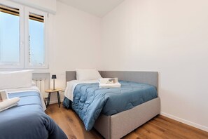 Quarto com cama, mesa de cabeceira, luminária e janela.