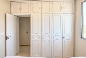 Ein Schlafzimmer mit einem Bett, einem Schrank mit mehreren Türen und einem Fenster.