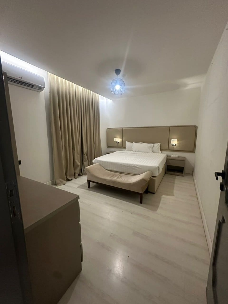 A hotel room with a bed, bedside tables, a ceiling fan, and a wardrobe.