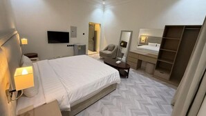 Habitación de hotel con cama, mesita de noche, silla, escritorio, espejo, armario y televisor.