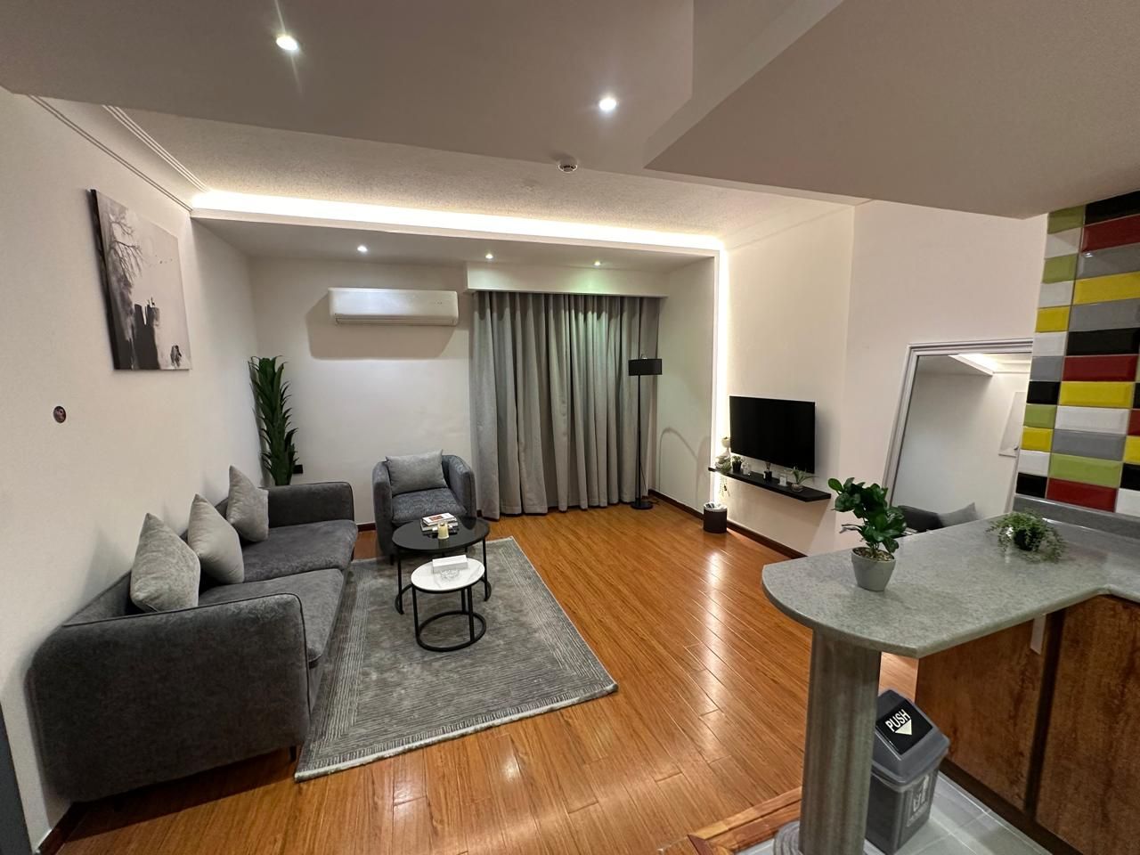 A modern living room with a grey sofa, a coffee table, and a TV.