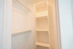 A closed closet with white shelving units and a visible door handle. - The Winsome Western - HotTub - Fire Pit - PingPong (Lubbock)