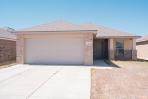 A single-story house with a garage, a brick exterior, and a clear sky. - The Winsome Western - HotTub - Fire Pit - PingPong (Lubbock)