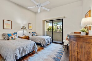 A bedroom with two beds, a ceiling fan, a large window, and a wooden dresser. - Desert Escape with Mountain Views (Oro Valley)