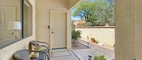 A room with a door, a window, a chair, a table, and a potted plant.