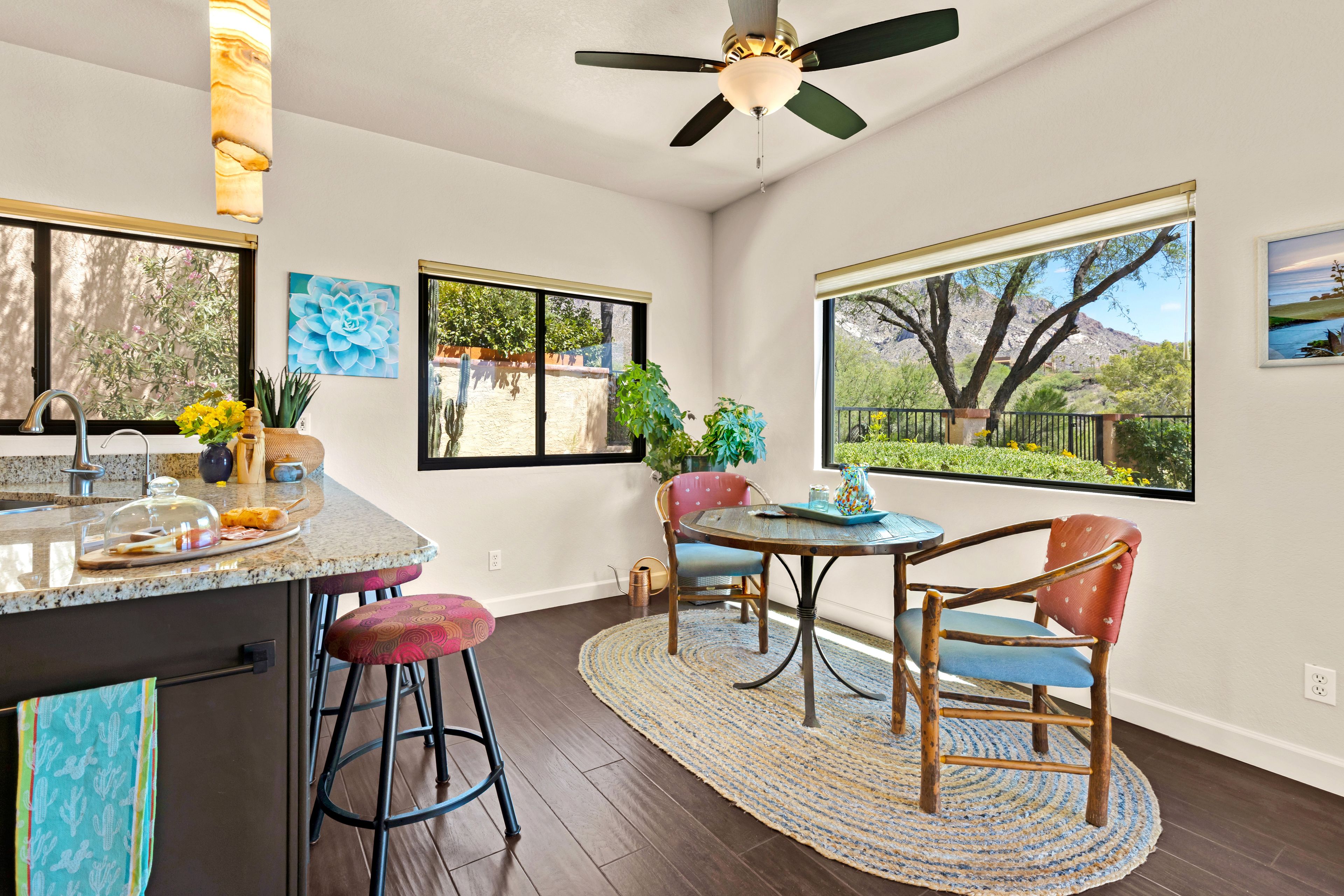 A kitchen with a granite countertop, a ceiling fan, and a dining area with a table and chairs.