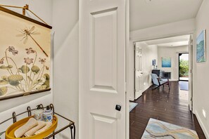 A hallway with a door leading to a room with a fireplace, a painting on the wall, and a rug on the floor. - Desert Escape with Mountain Views (Oro Valley)