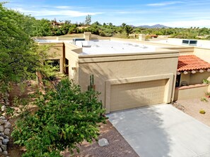 A residential building with a flat roof, a garage, and a garden area with various plants. - Desert Escape with Mountain Views (Oro Valley)