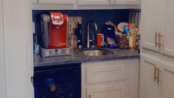 A kitchen with white cabinets, a coffee machine, and various kitchen items.