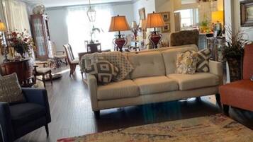 A living room with a sofa, chairs, a patterned rug, and a ceiling fan.